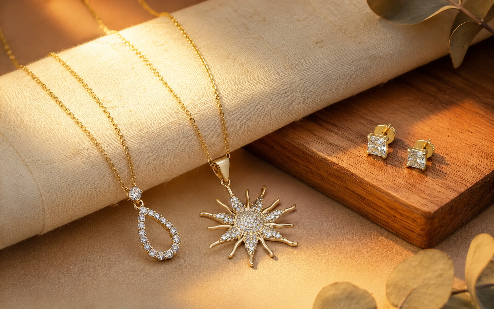 Gold necklaces and stud earrings displayed on a warm wooden jewelry setup.