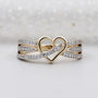 Gold heart-shaped ring with diamond accents on a light background

