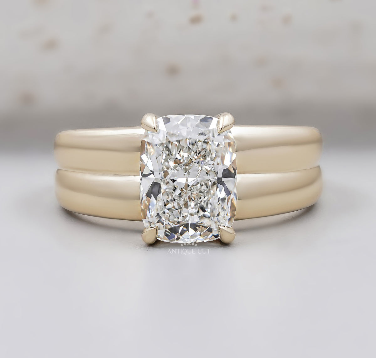 Radiant cut diamond engagement ring with wide yellow gold band and four prong setting