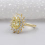 Gold ring with a yellow diamond and smaller diamonds on a white background

