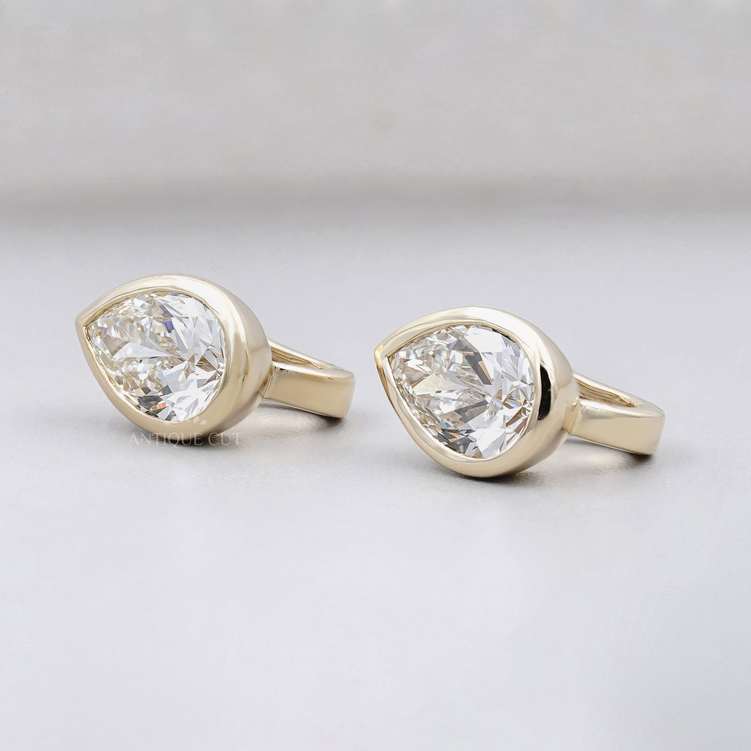 Pear cut diamond stud earrings in a bezel setting crafted in yellow gold