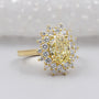 Gold ring with a yellow diamond and smaller diamonds on a white background

