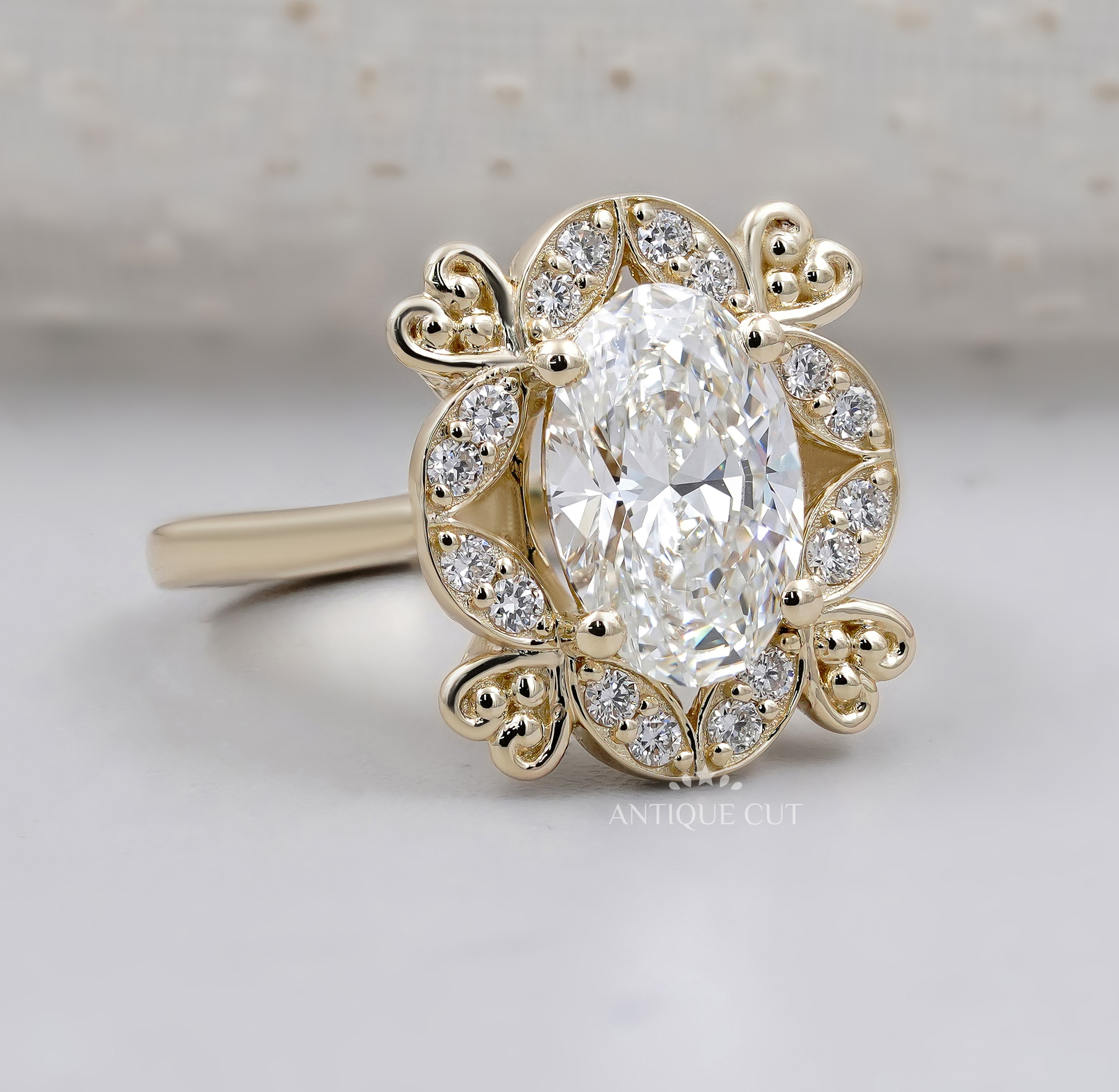 Oval cut diamond ring surrounded by round diamonds and floral gold details