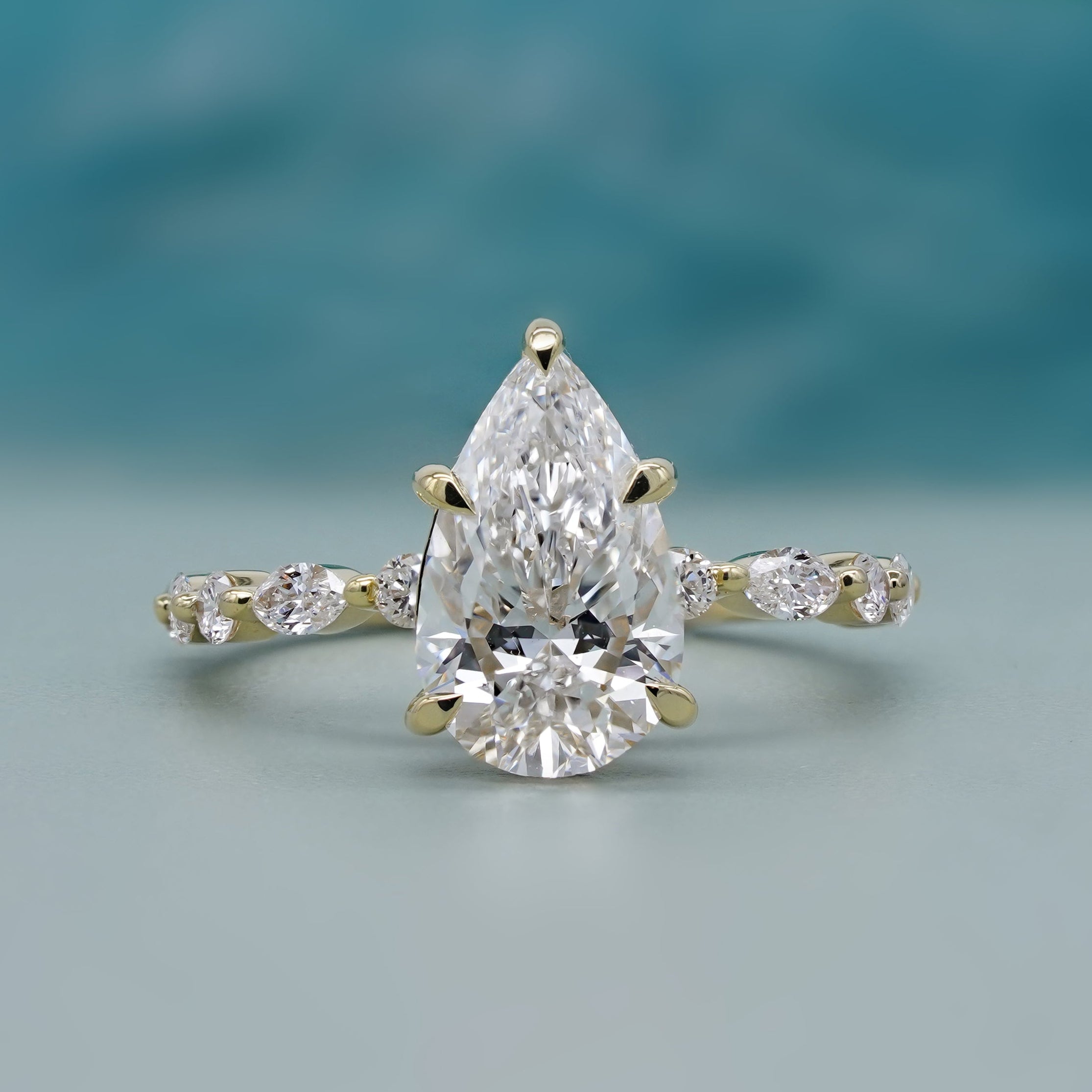 Pear side stone engagement ring in yellow gold