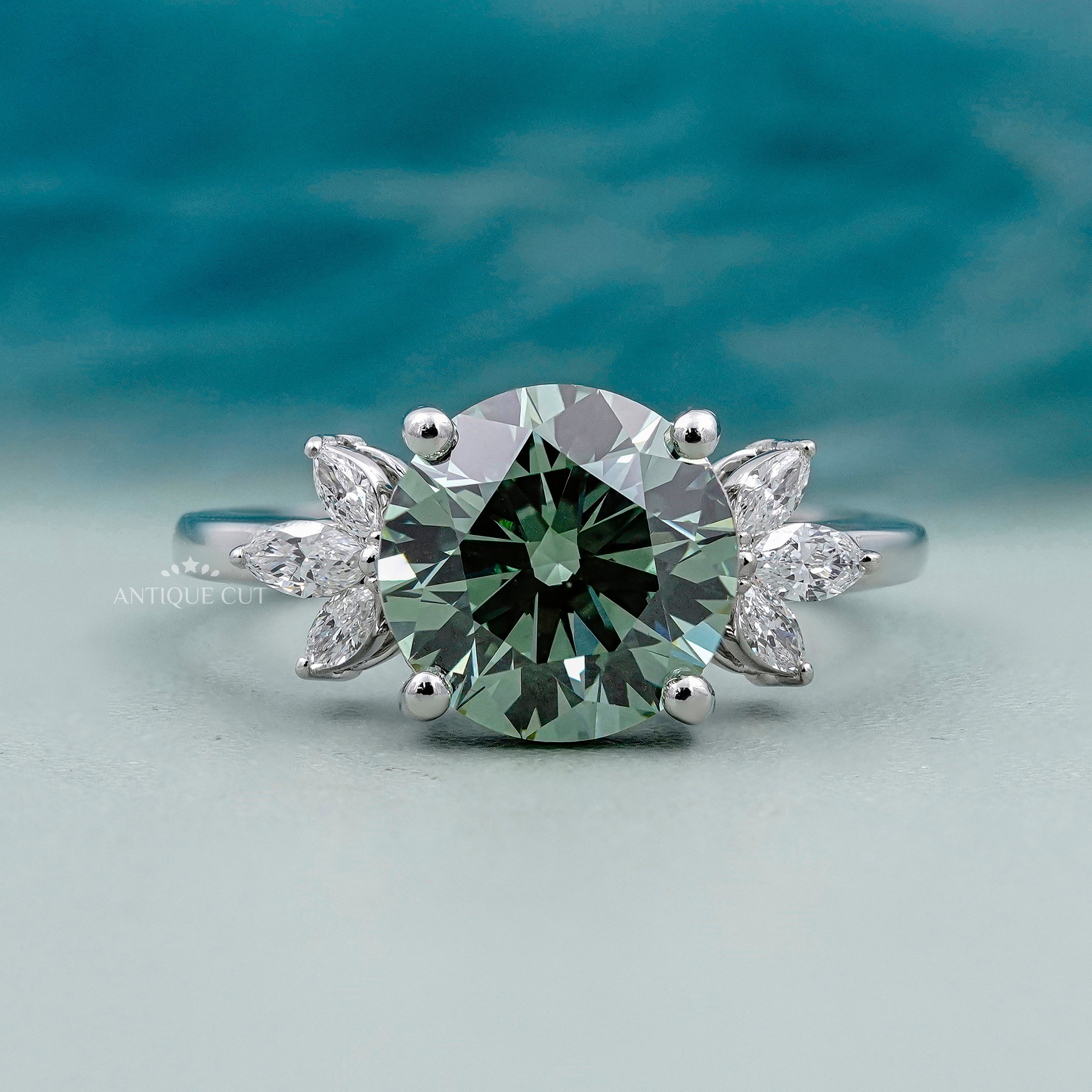 Round cut antique green diamond ring with marquise side stones