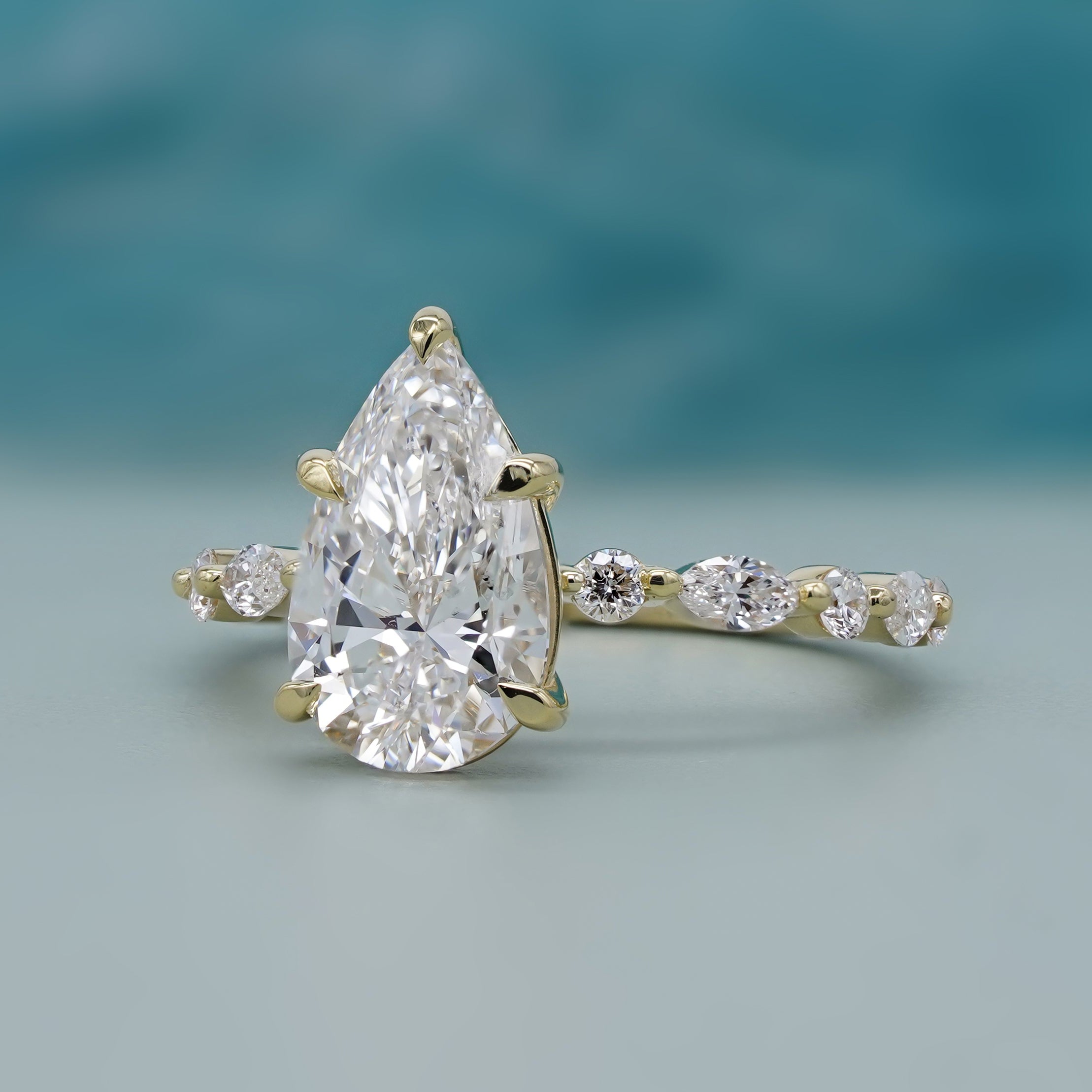 Lab grown pear side stone engagement ring yellow gold
