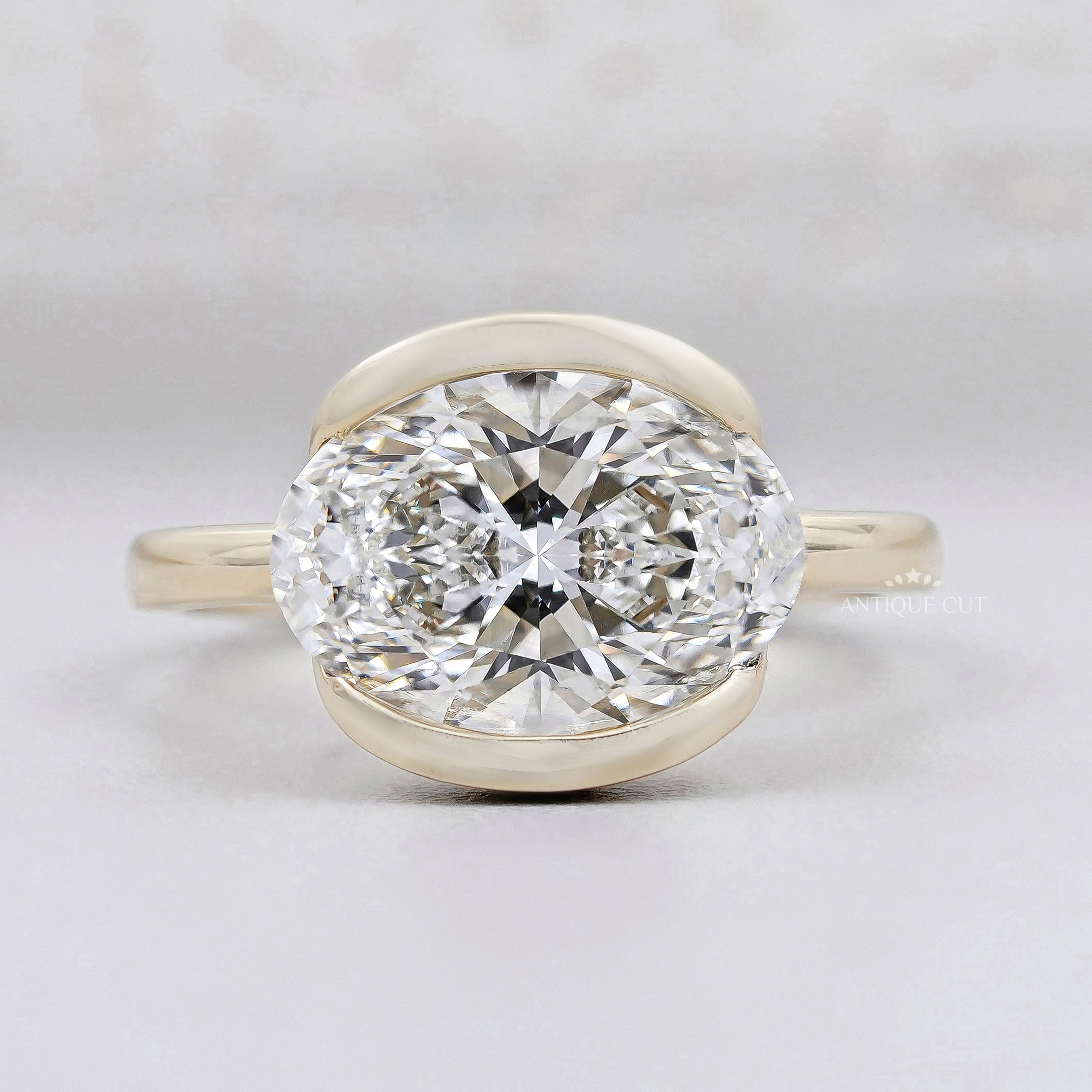 east west oval engagement ring bezel set yellow gold