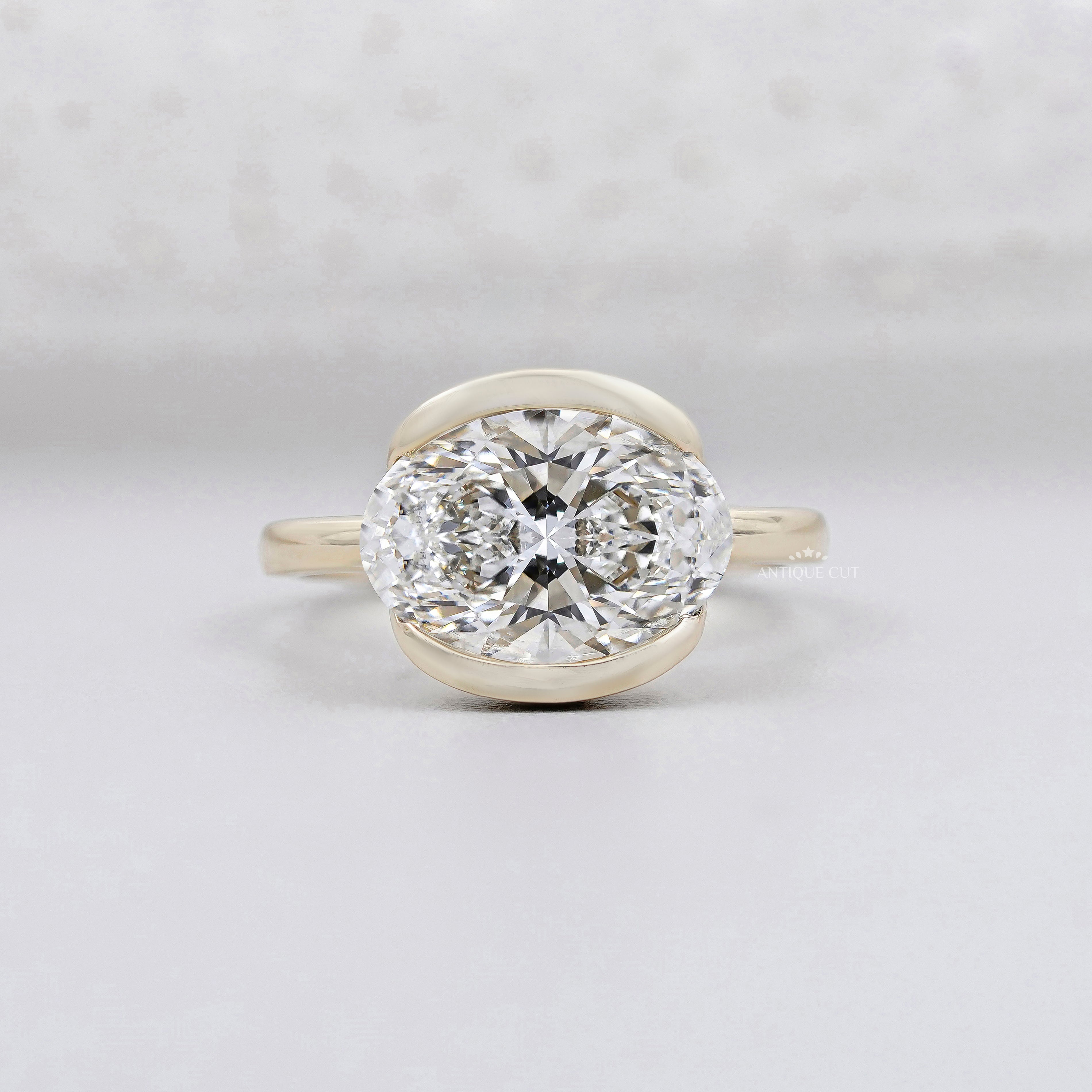 east west oval engagement ring bezel set yellow gold