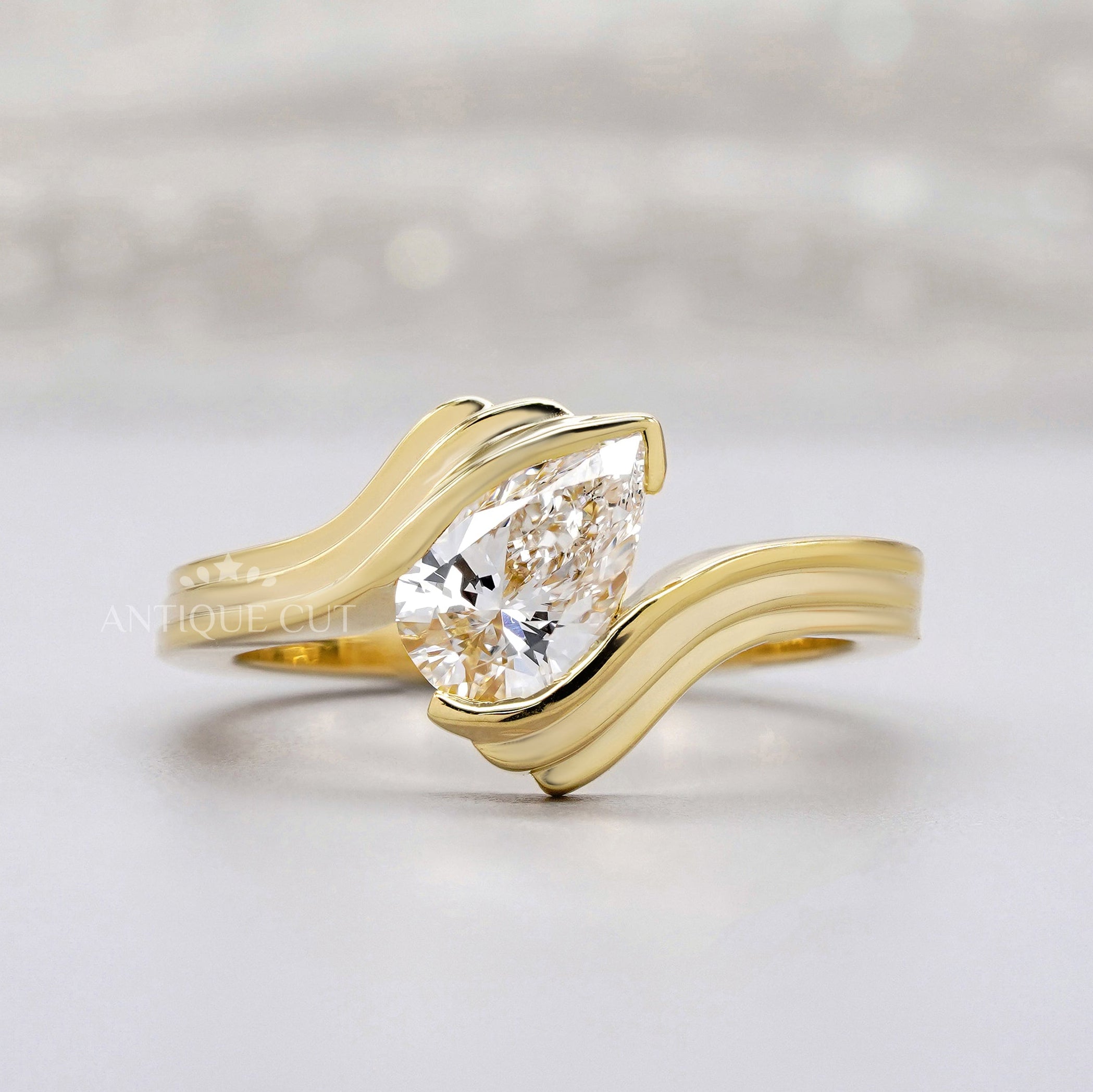 Pear solitaire engagement ring with wave diamond band in yellow gold