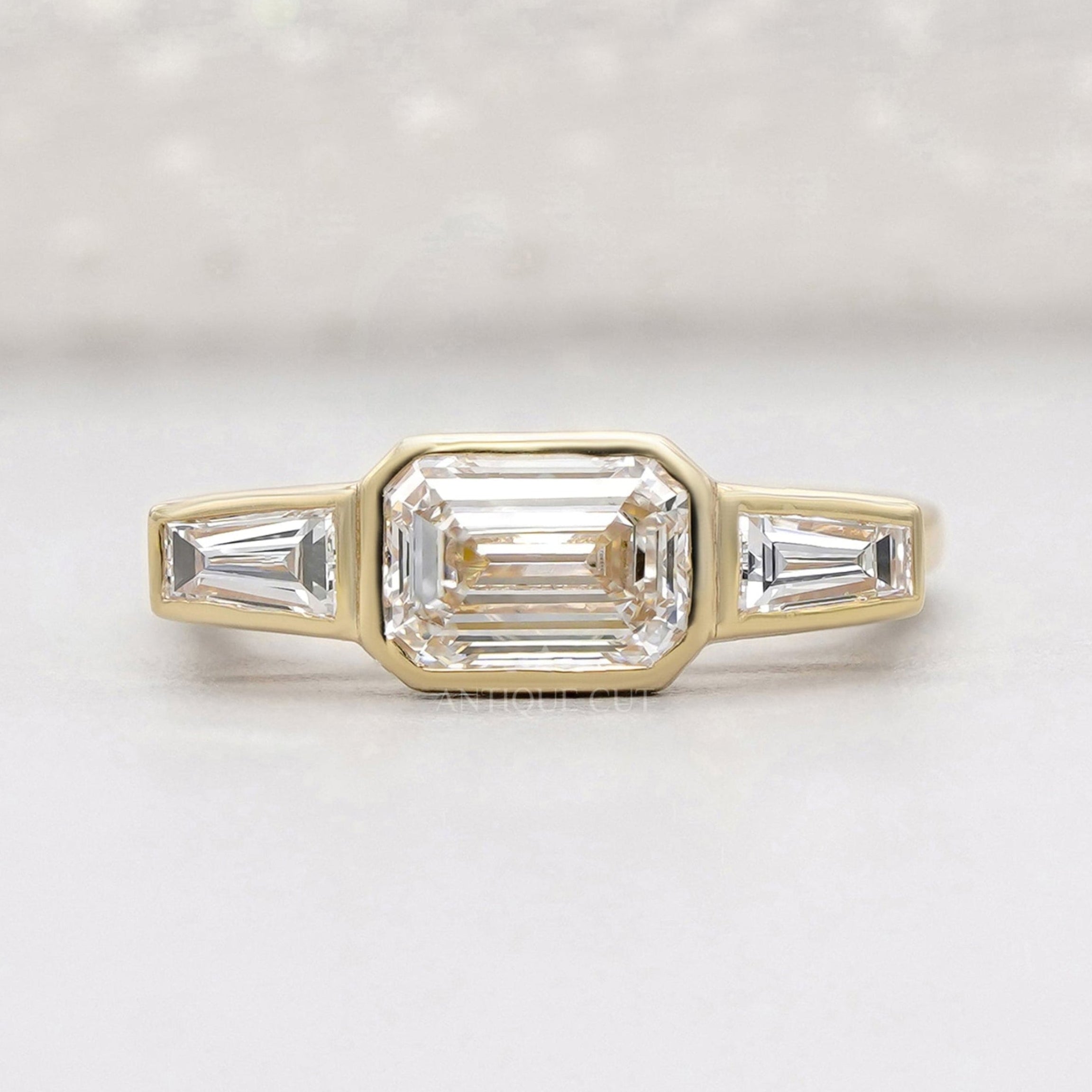 emerald three stone engagement ring in yellow gold