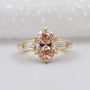 Gold ring with a pink diamond and baguette cut diamonds on a light background