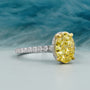 Ring with a large yellow gemstone and smaller diamonds on a blurred natural background