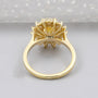 Gold ring with a yellow diamond and smaller diamonds on a white background

