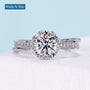 Floral halo engagement ring with round cut diamond and twisted pavé band
