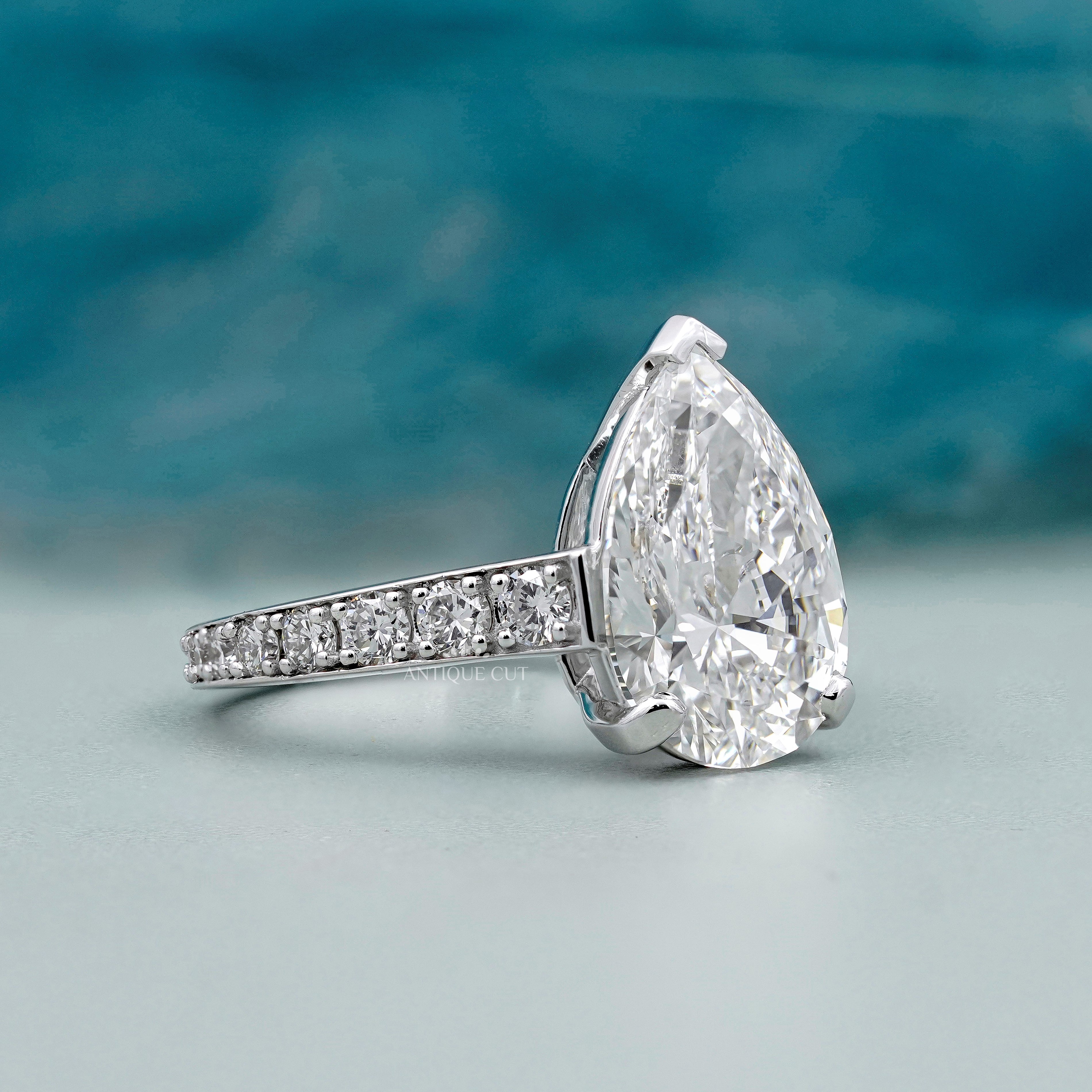 Pear cut diamond ring with V prong setting and white gold pavé band