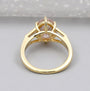Gold ring with a pink diamond and baguette cut diamonds on a light background