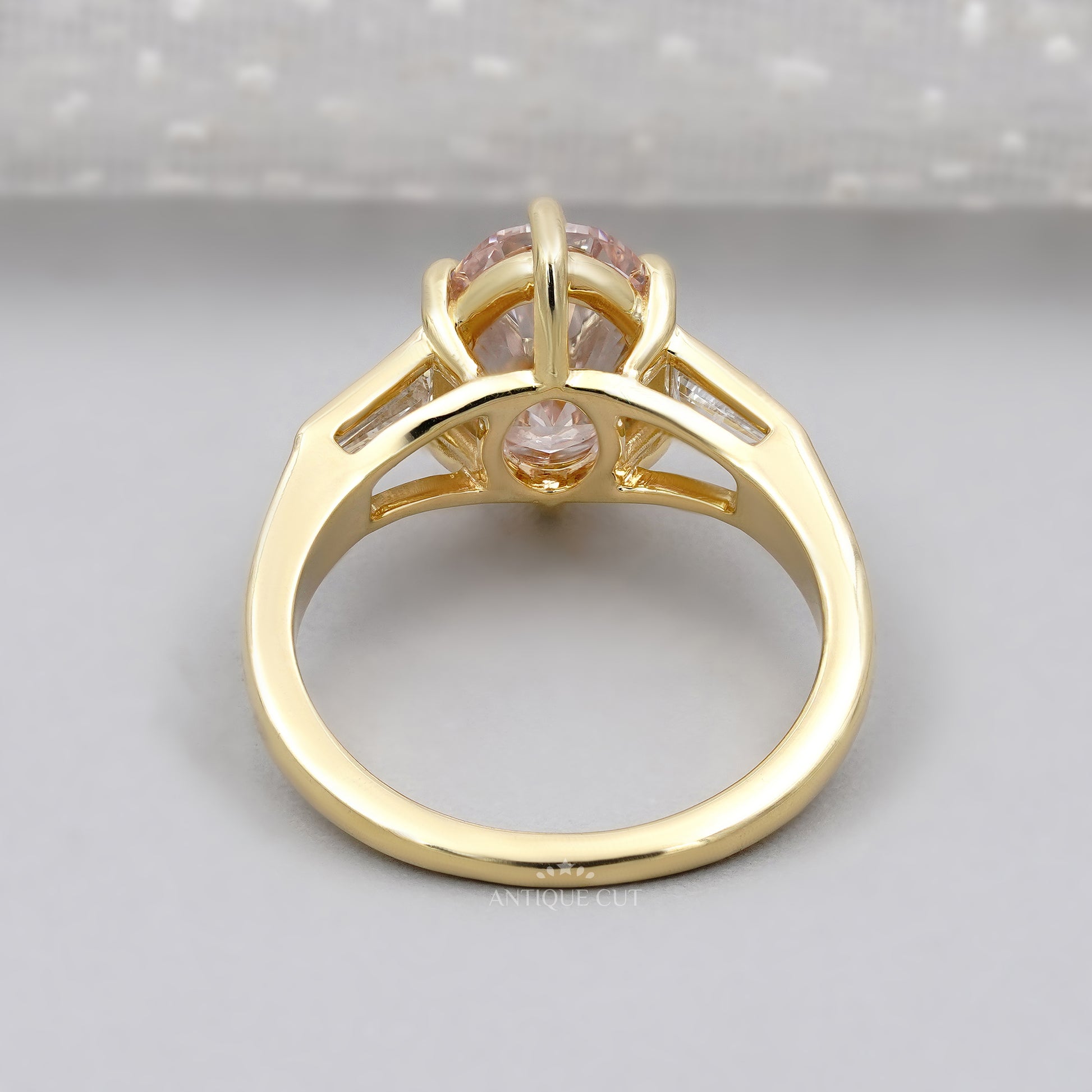 Gold ring with a pink diamond and baguette cut diamonds on a light background