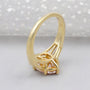 Gold ring with a pink diamond and baguette cut diamonds on a light background