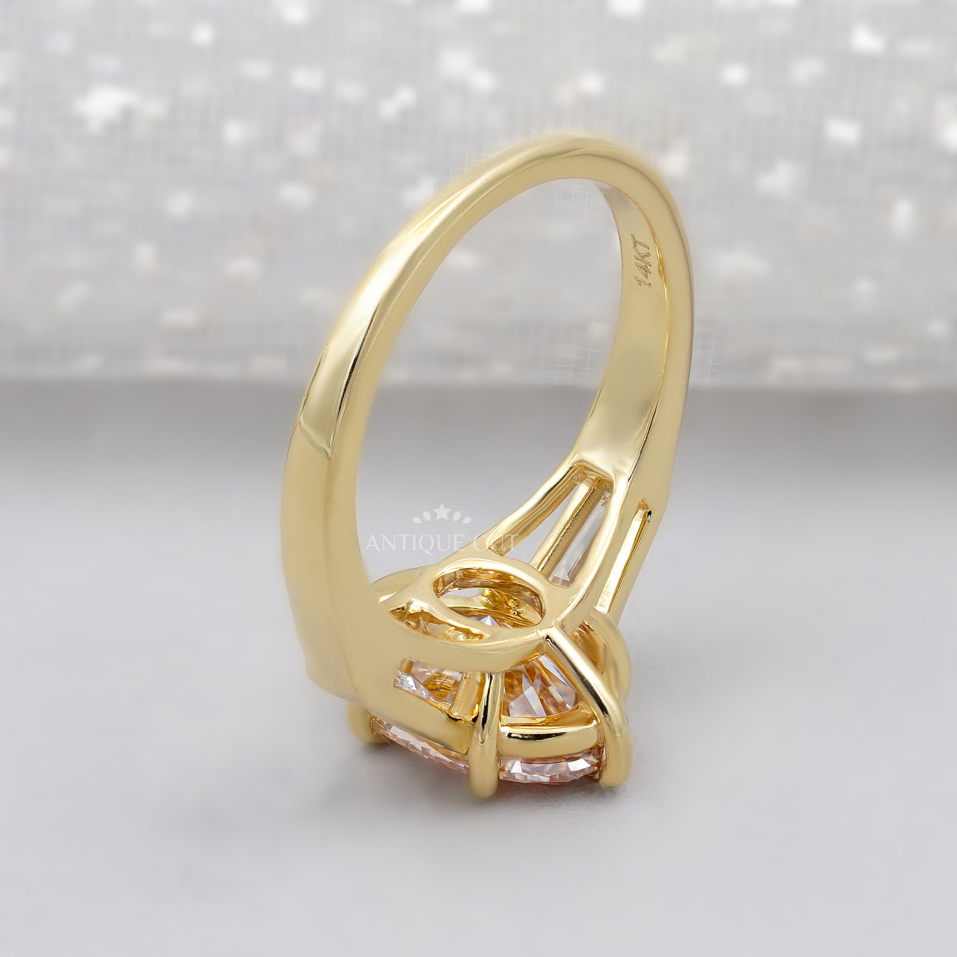 Gold ring with a pink diamond and baguette cut diamonds on a light background
