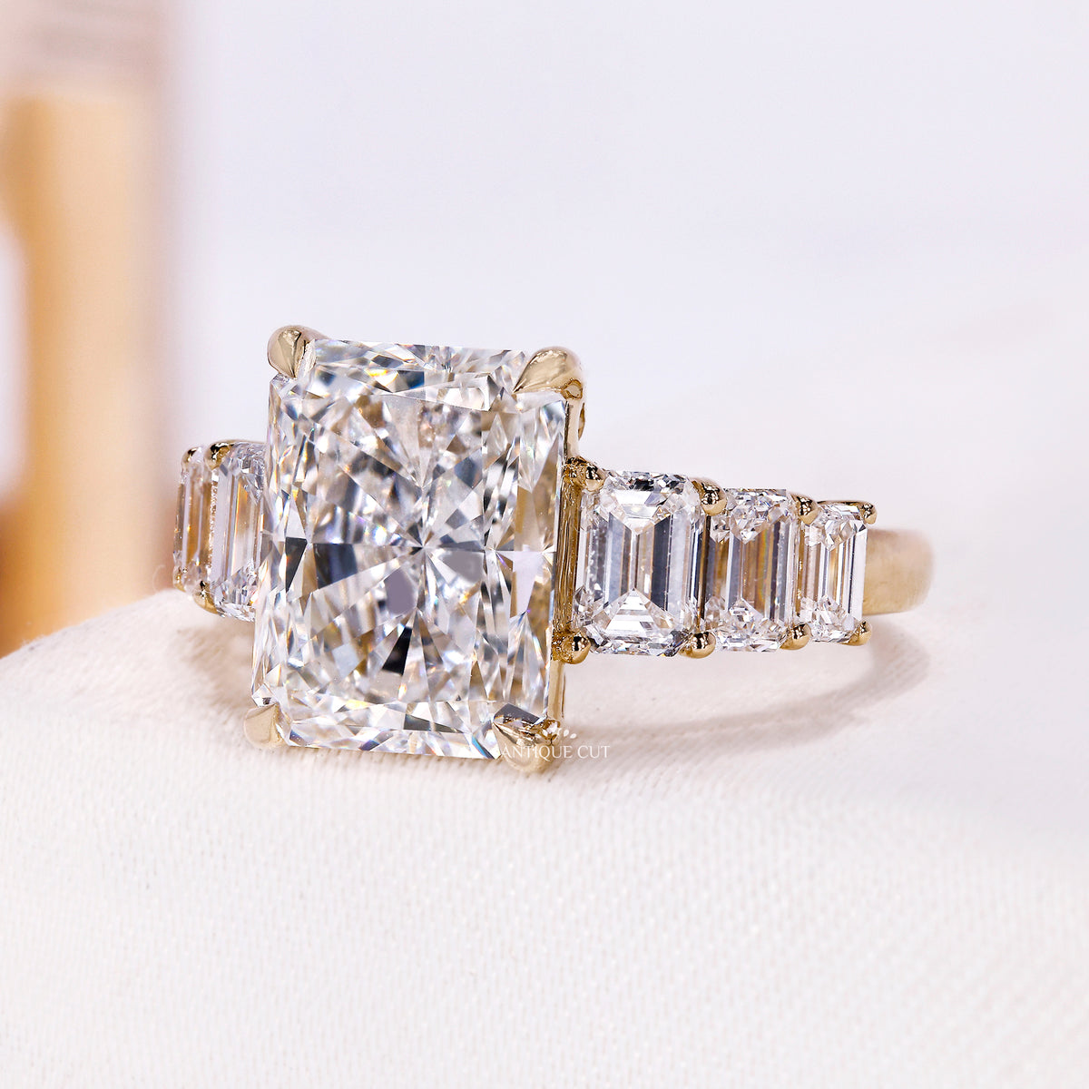 Side view of yellow gold engagement ring with emerald cut side stones