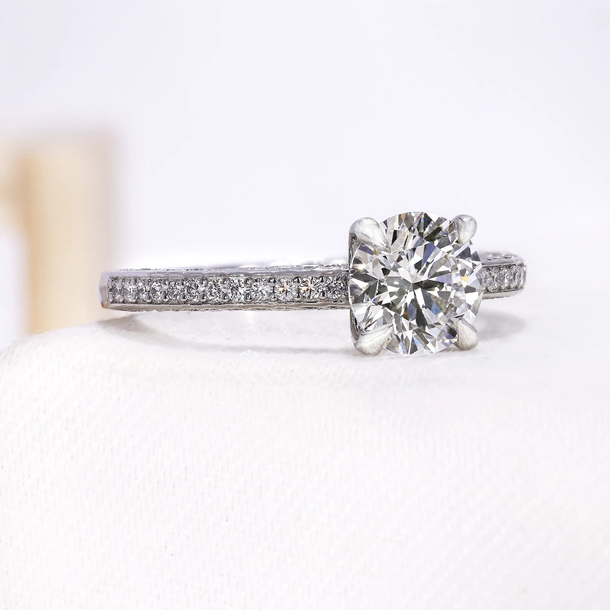Round center diamond held by four prongs above a pavé band