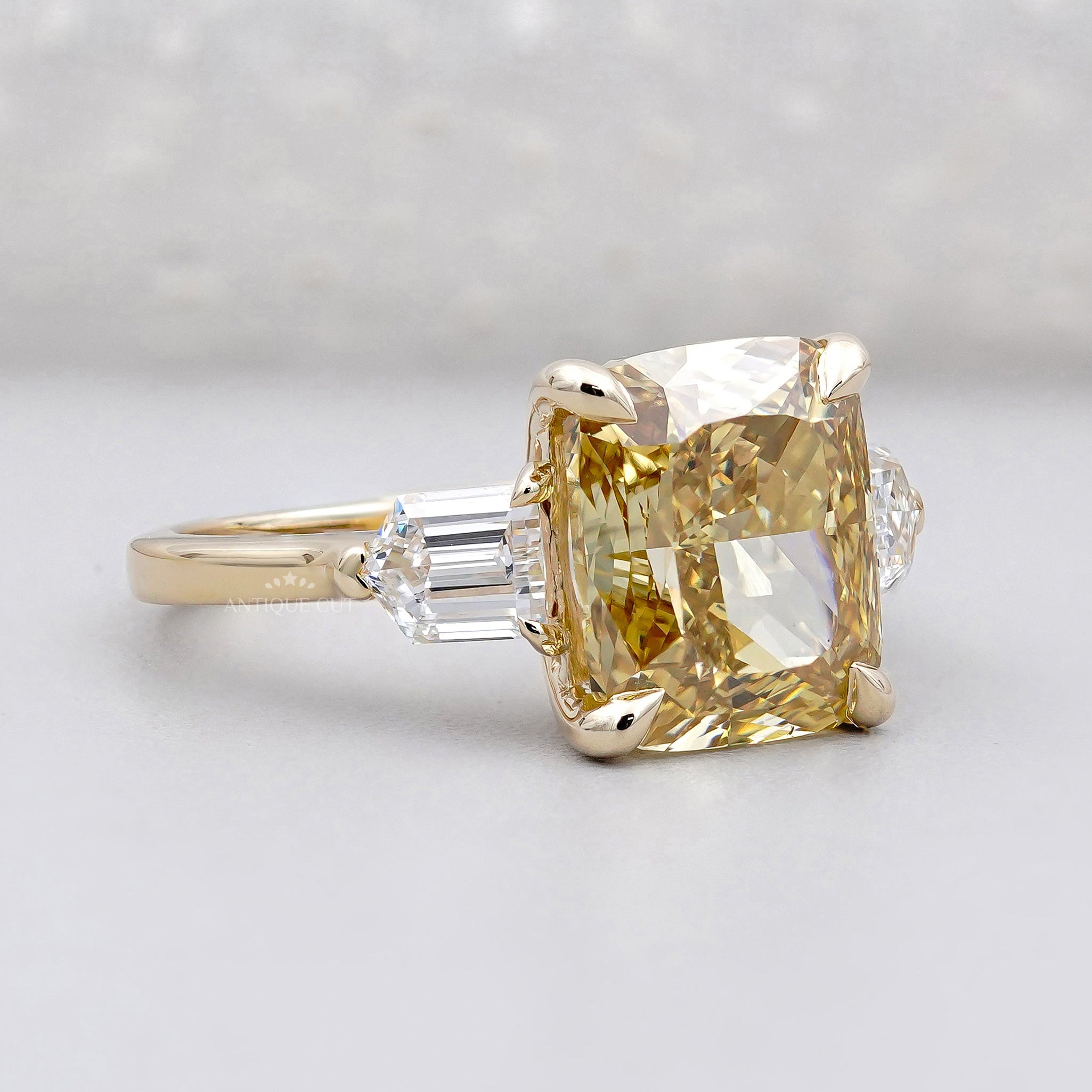 Gold ring with a large yellow diamond and smaller clear diamonds on a light gray background

