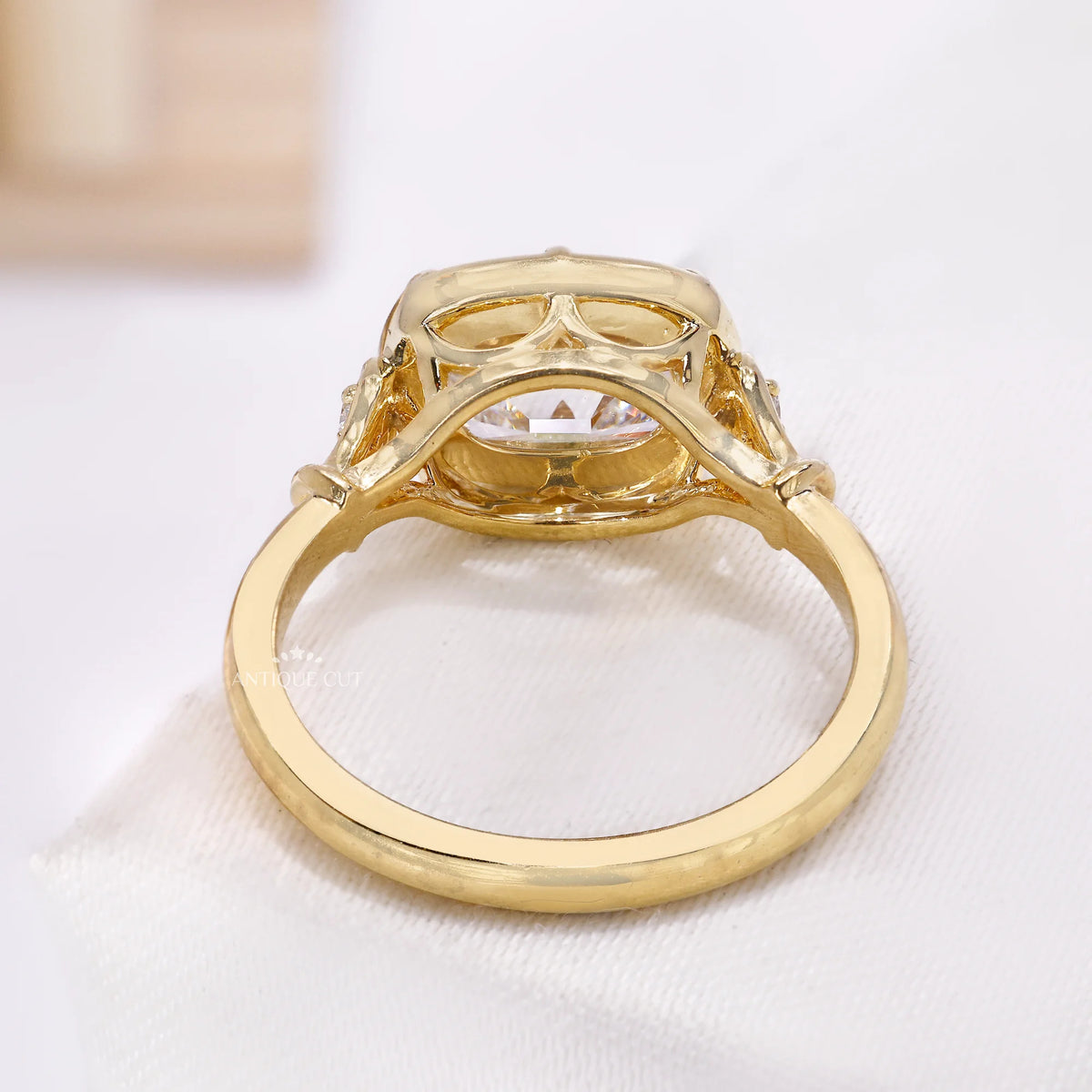 Close-up of scalloped yellow gold setting around the cushion diamond