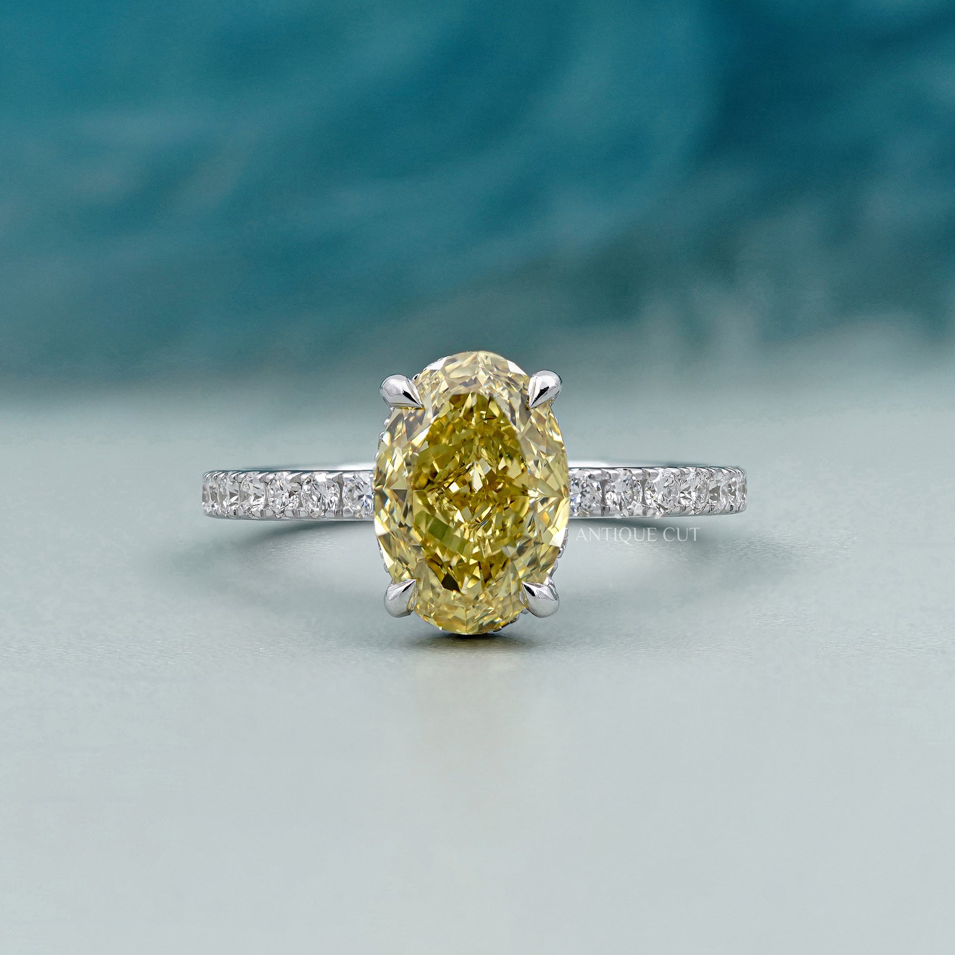 Ring with a yellow diamond and smaller diamonds on a gradient background

