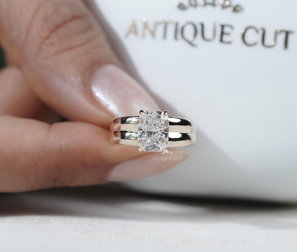 Wide band yellow gold engagement ring with radiant cut center diamond