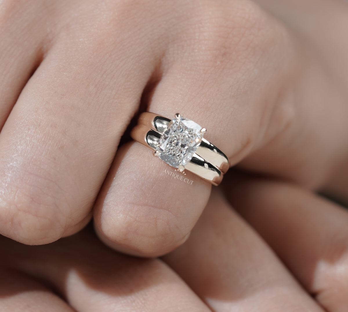 Wide band yellow gold engagement ring with radiant cut center diamond
