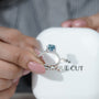 Close-up of a hand wearing a ring with a blue gemstone on a natural background

