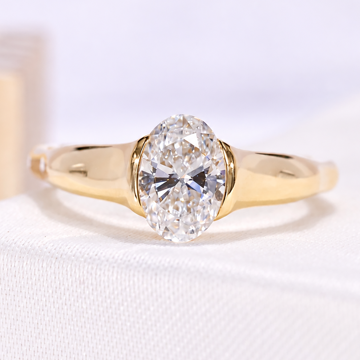 Oval lab grown diamond ring with yellow gold half bezel solitaire design