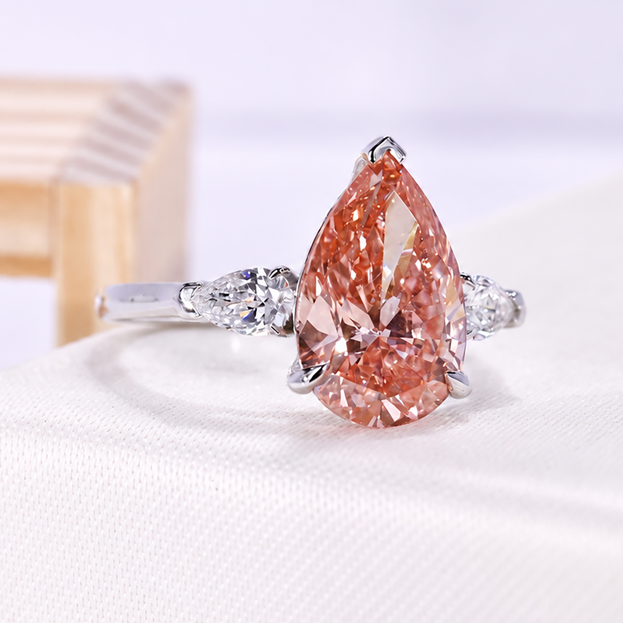 Three stone engagement ring featuring fancy pink pear lab grown diamond center