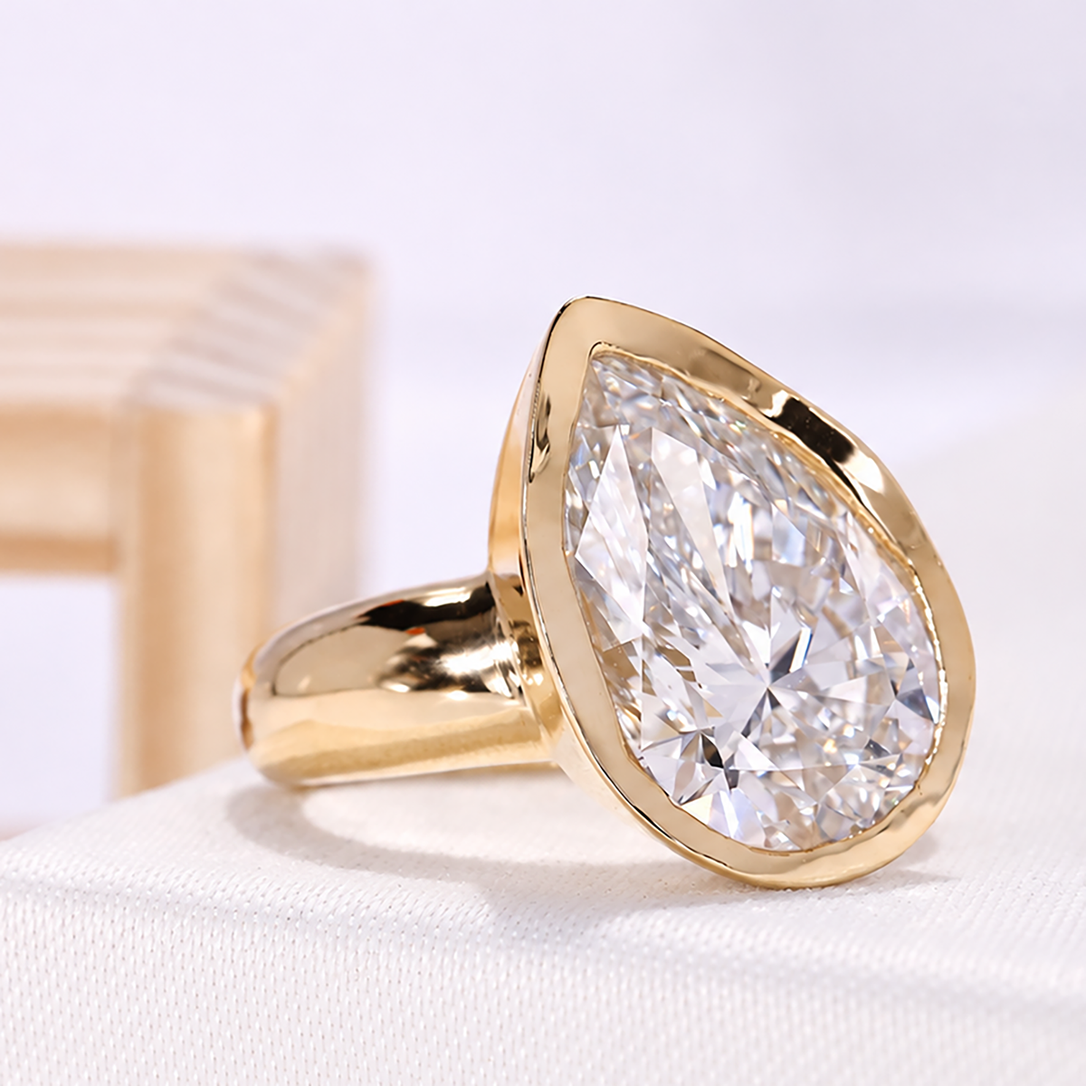 Yellow gold diamond ring featuring pear shaped lab grown diamond and bezel setting