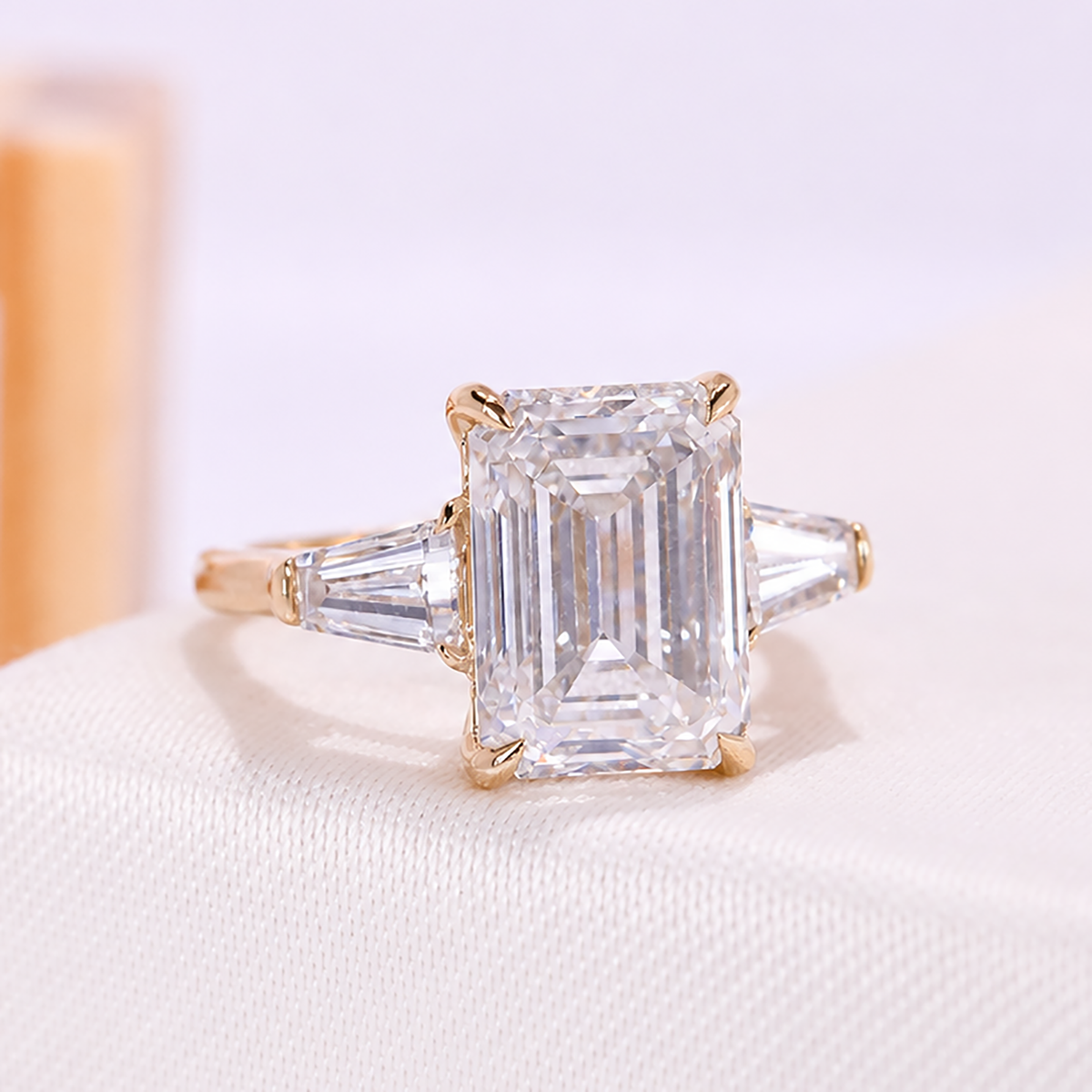 Emerald cut engagement ring with side stones in yellow gold