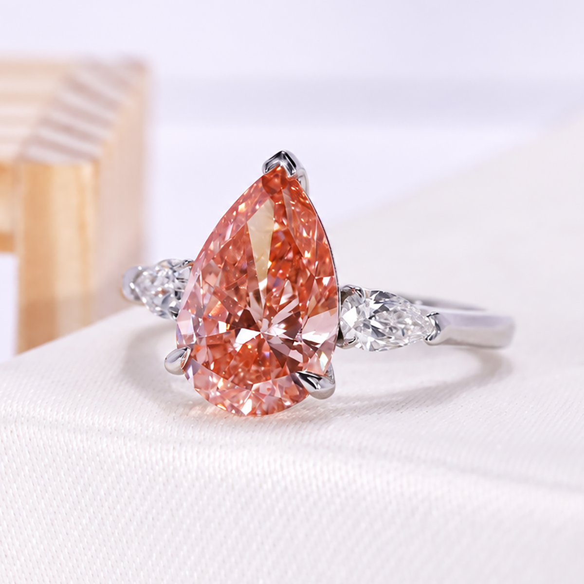 Lab grown pear diamond ring with pink center stone and three stone setting