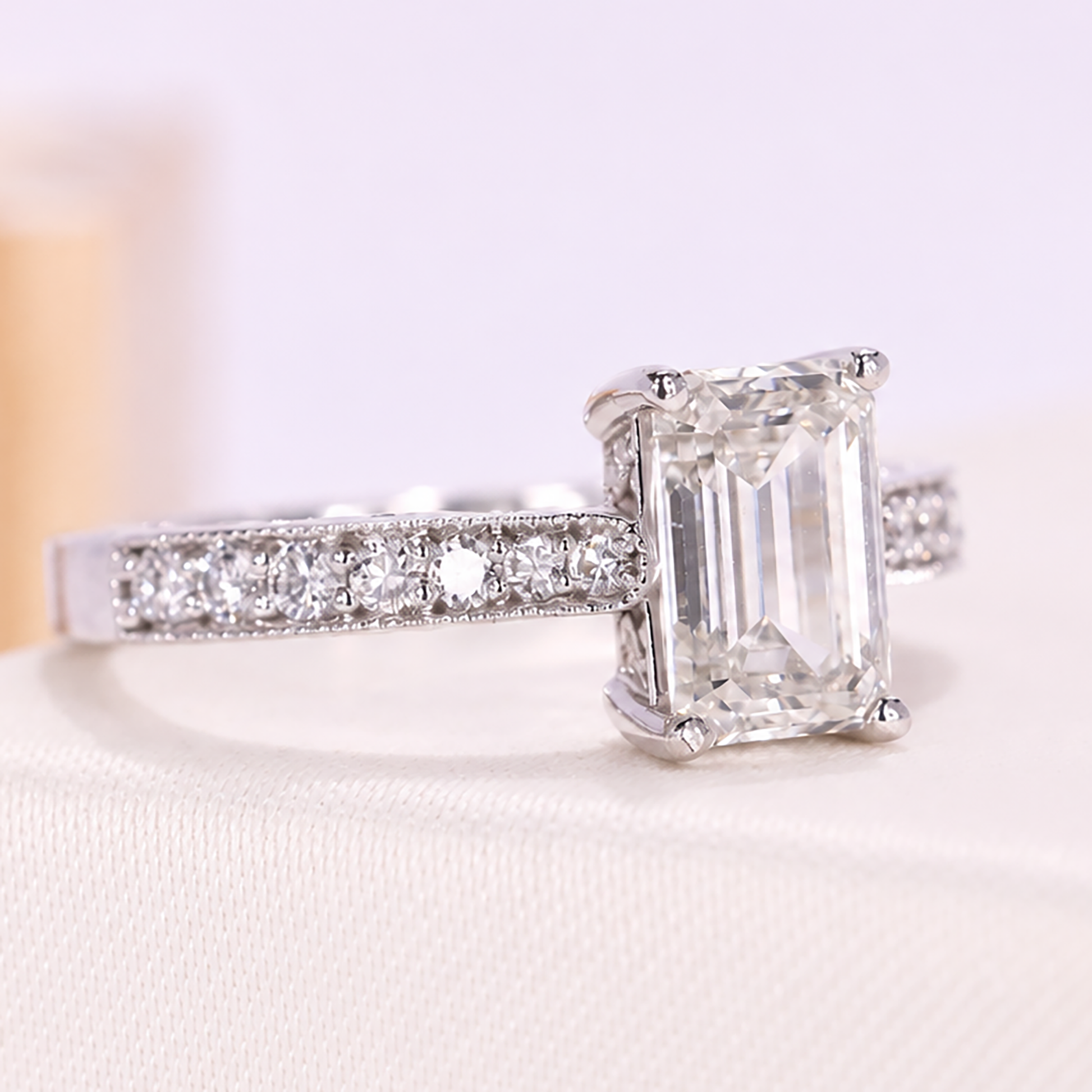 Close-up of an emerald-cut diamond engagement ring with a pavé diamond band.