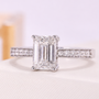 Emerald-cut diamond engagement ring featuring a pavé band and cathedral-style setting.