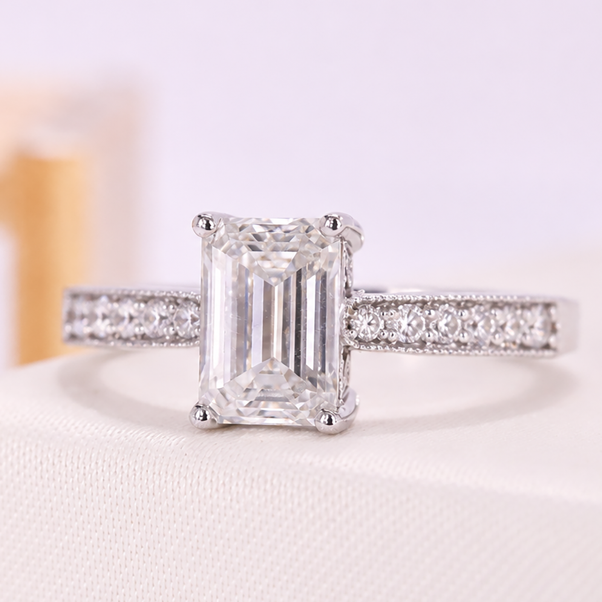 Emerald-cut diamond engagement ring featuring a pavé band and cathedral-style setting.