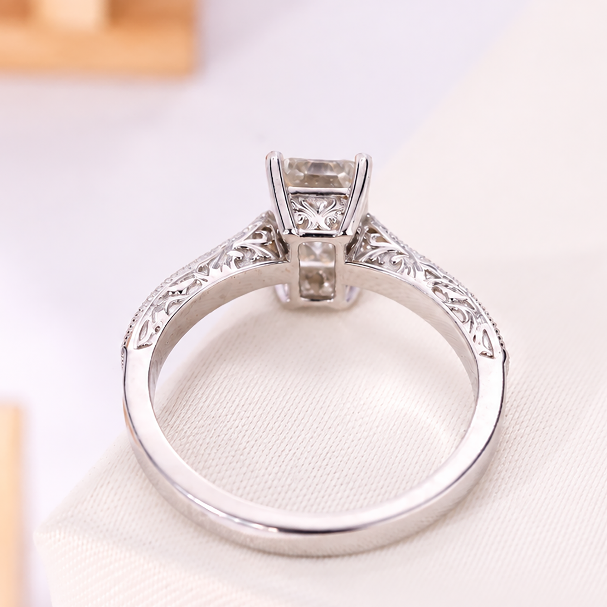 Emerald-cut diamond ring in a white metal setting with detailed shoulders.