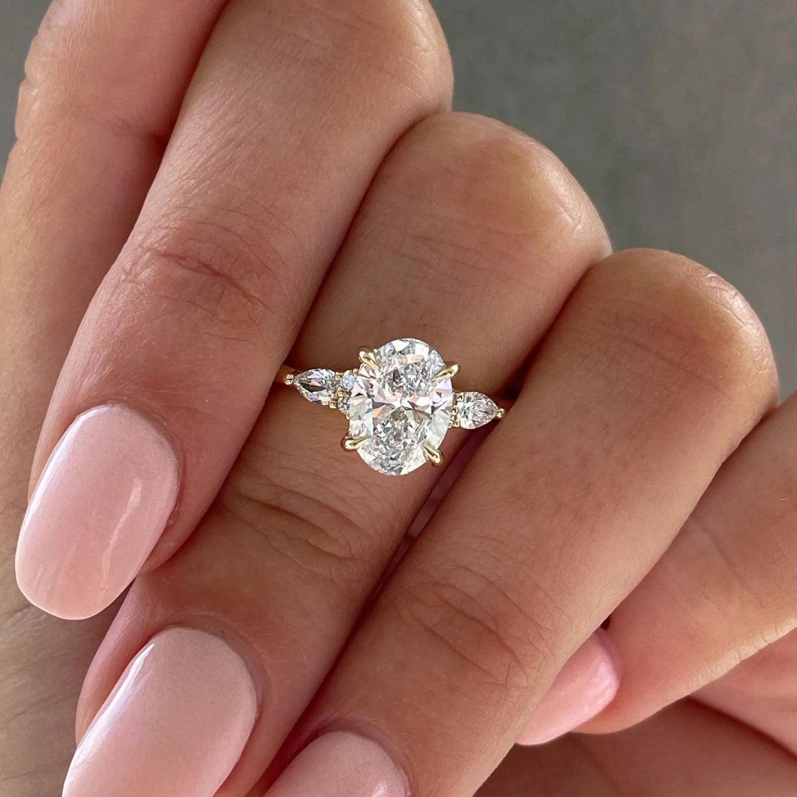 Oval diamond engagement ring with pear side stone 