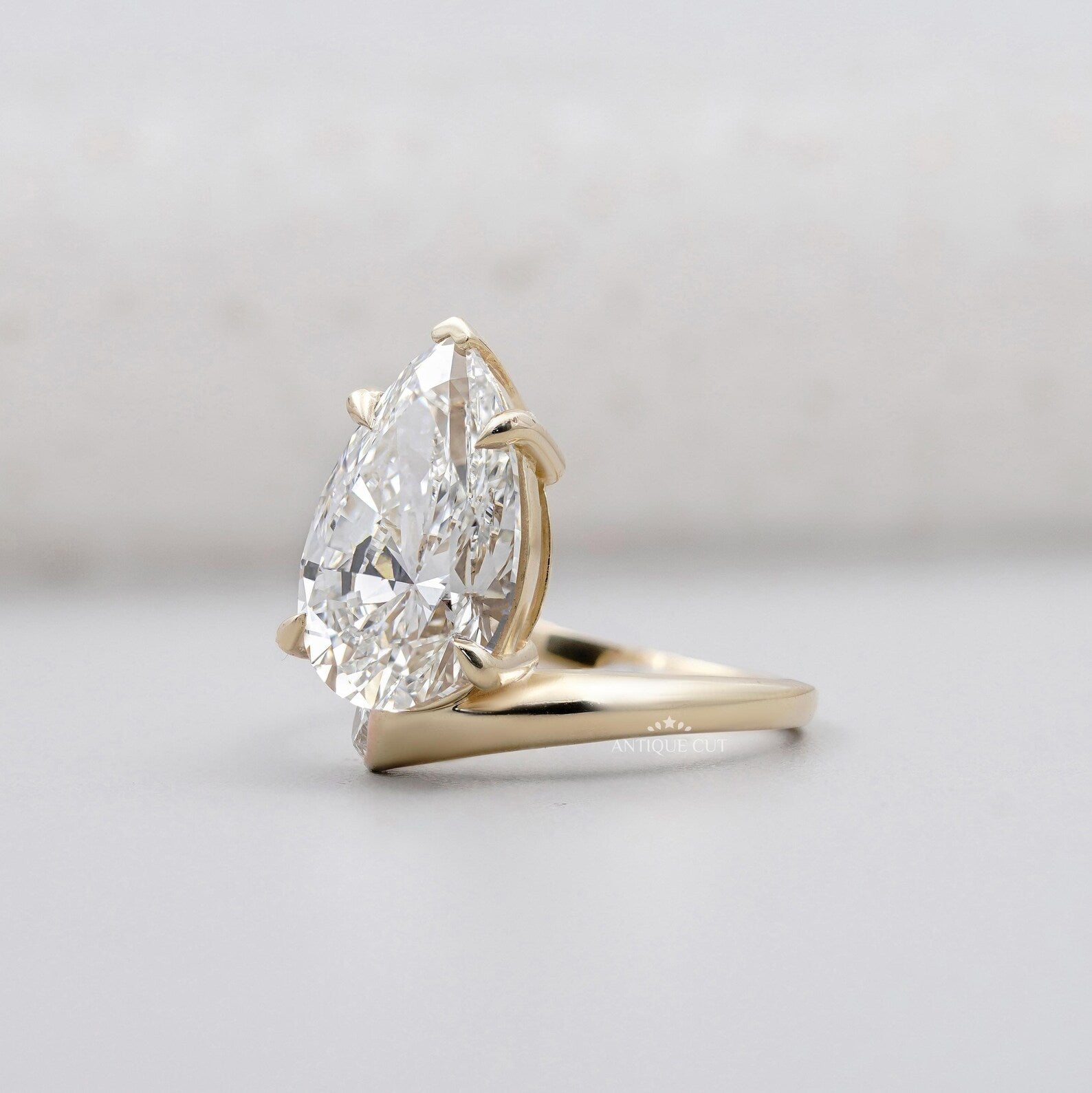 Yellow gold pear shaped engagement ring with claw prongs and side diamonds