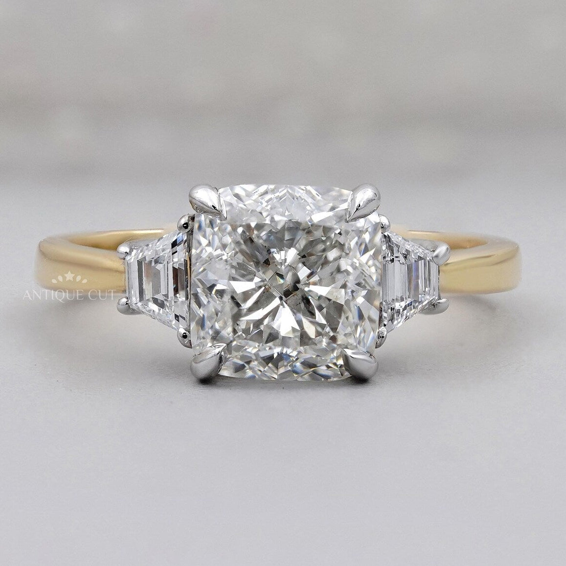 Cushion cut three stone ring in yellow gold