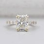 Cushion cut engagement ring with double claw prongs and pavé band in yellow gold