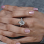 Close-up of a hand wearing a diamond ring with a blurred background

