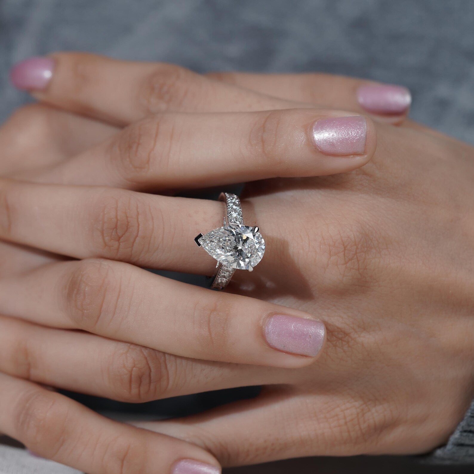 Close-up of a hand wearing a diamond ring with a blurred background

