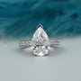 Diamond ring with a pear-shaped center stone on a light gray background

