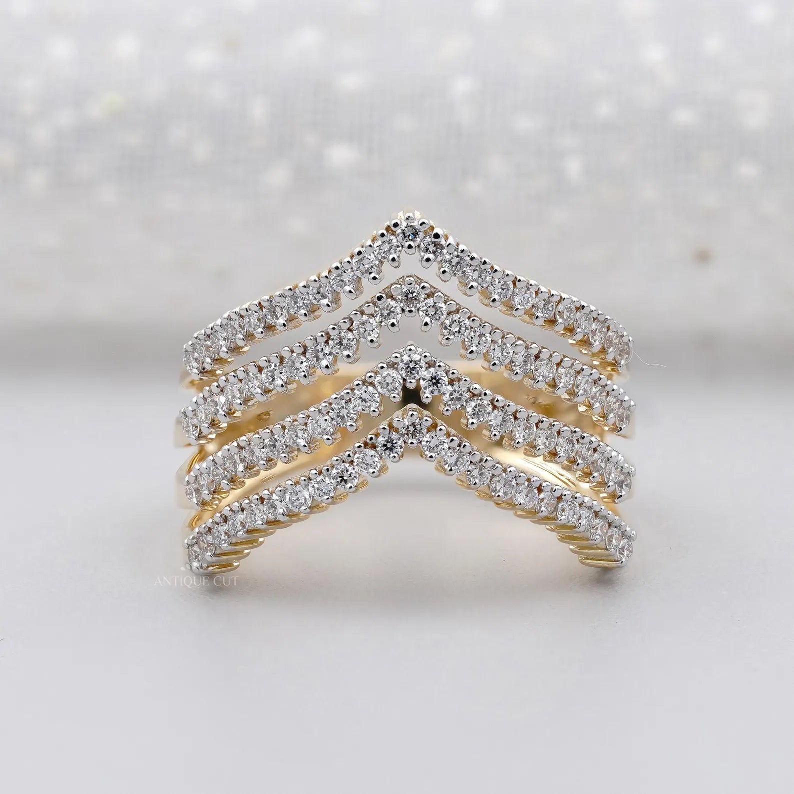 Gold and diamond chevron ring on a light background
