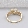 Gold ring with a heart and infinity symbol on a light gray background

