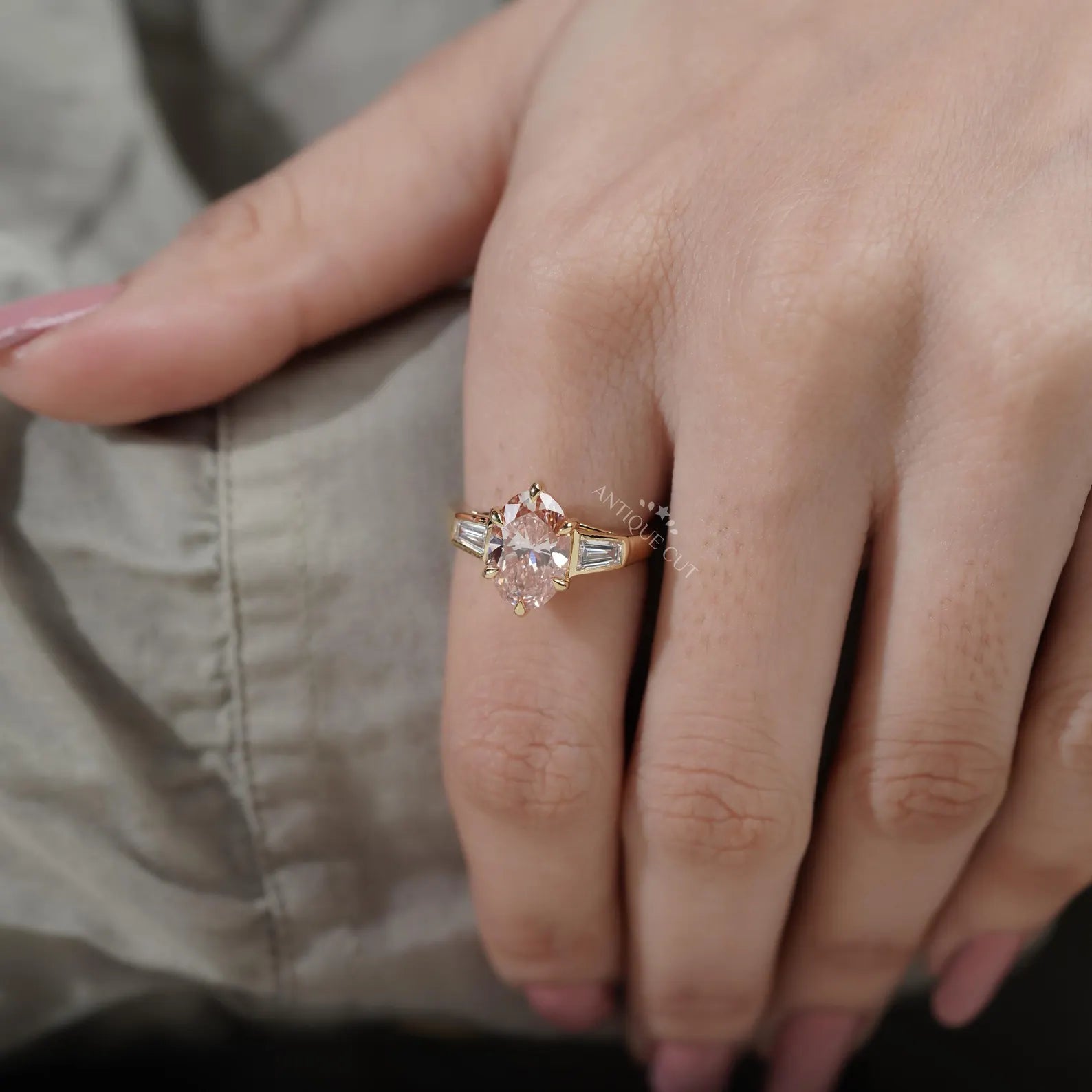 Close-up of a hand wearing a rose gold ring with a pink gemstone.

